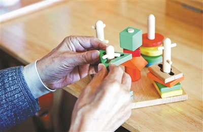 老人在护理员的陪同下玩益智玩具，多动脑多动手，有益于保持一定的生活自理能力
