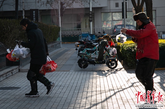 12月17日，北京中关村，两位外卖员正要进入办公楼送餐。中国青年报·中国青年网见习记者 张玉佳/摄