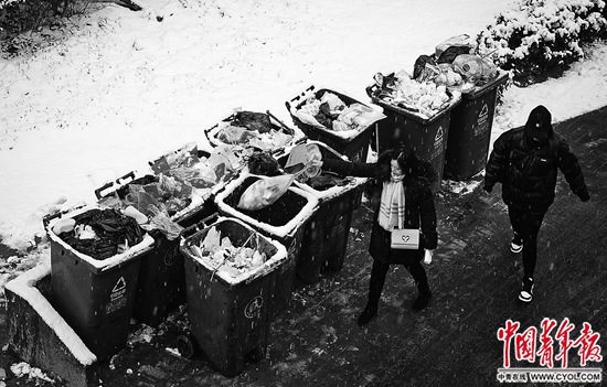 12月16日，北京朝阳区一小区内，住户将垃圾袋投放到路边的垃圾桶。中青报·中青网见习记者 张玉佳/摄