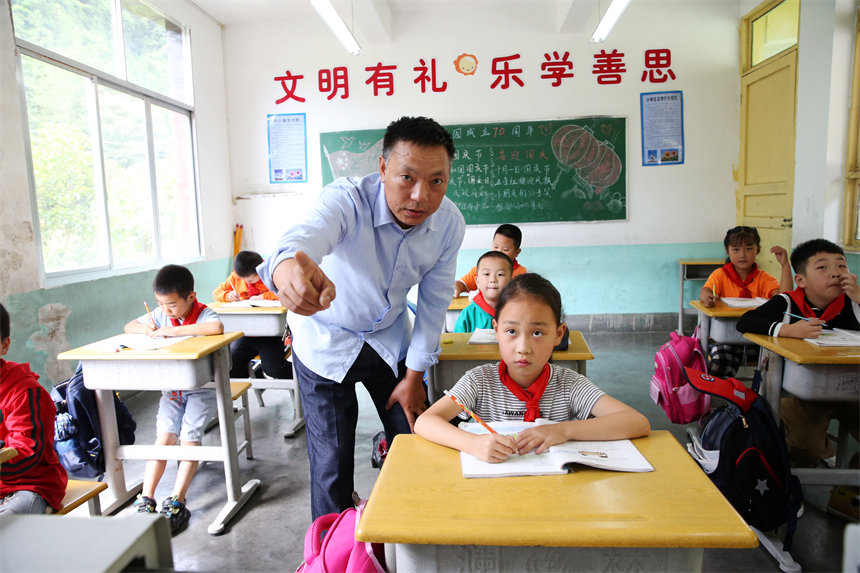 重庆市黔江区小南海镇后坝小学,老师何祖良在辅导学生做作业.杨敏摄